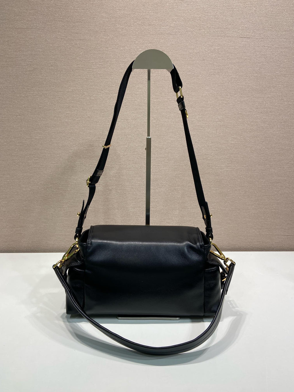 Prada black leather shoulder bag with top handle, long strap, and gold hardware.