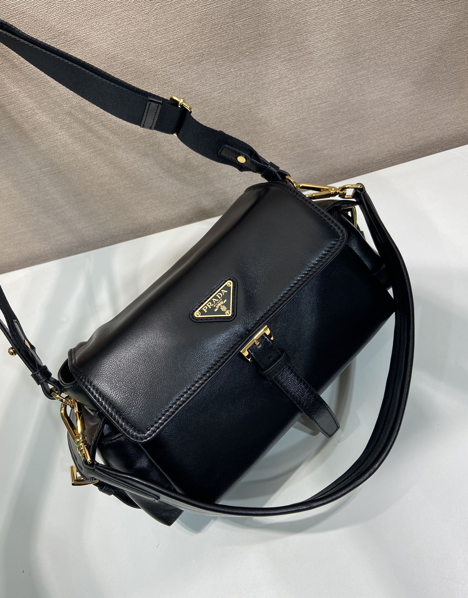 Prada black leather shoulder bag with logo plaque, flap closure, and gold chain strap.