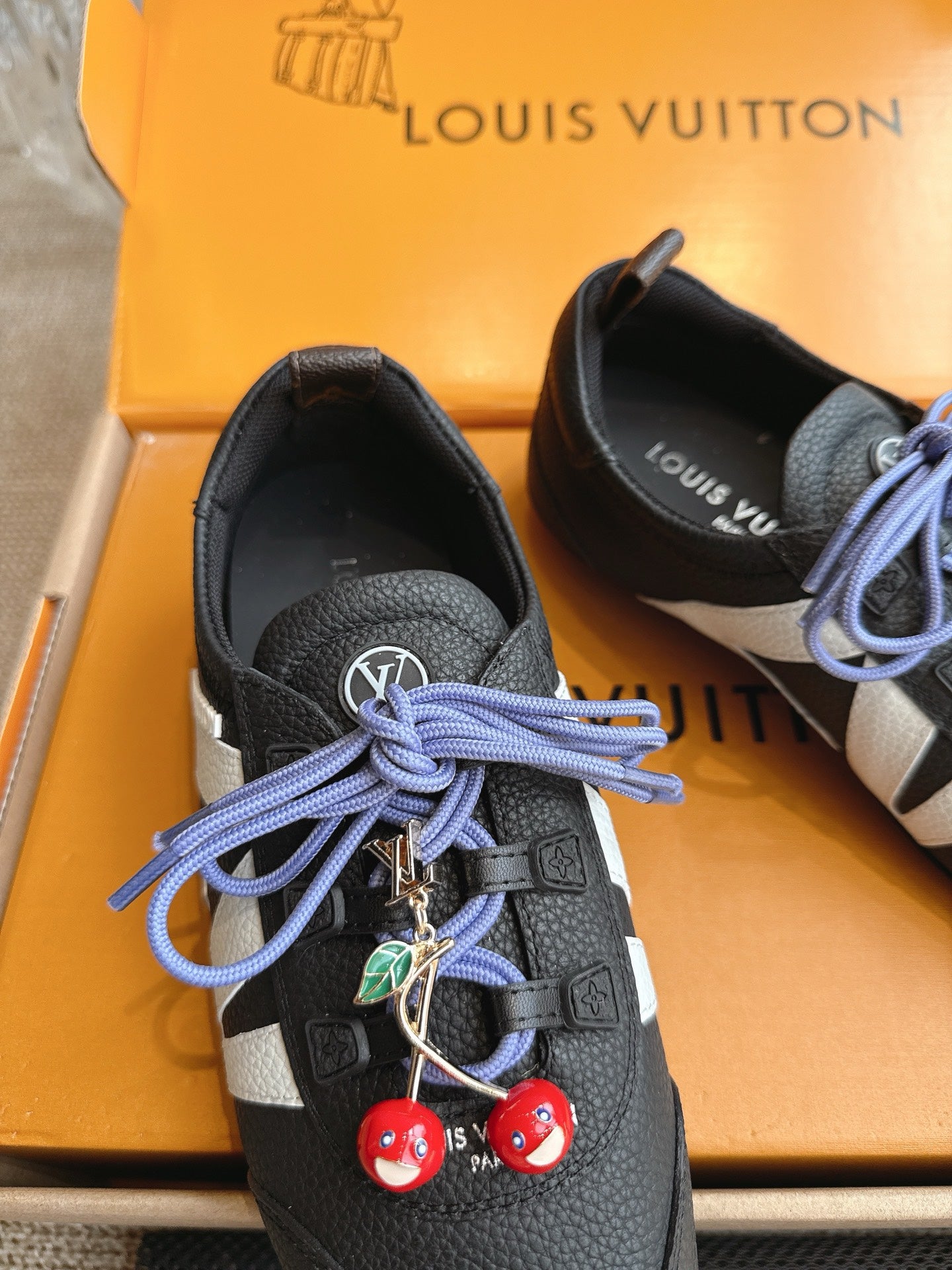 Louis Vuitton unisex sneakers detail: black leather, blue laces, red and green charms