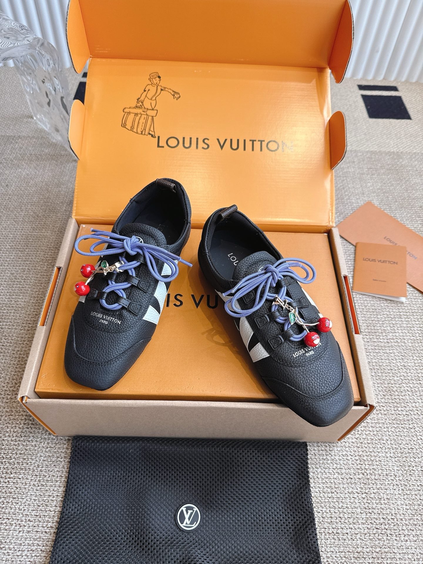 Louis Vuitton unisex sneakers, black leather uppers with blue laces and red bead charm