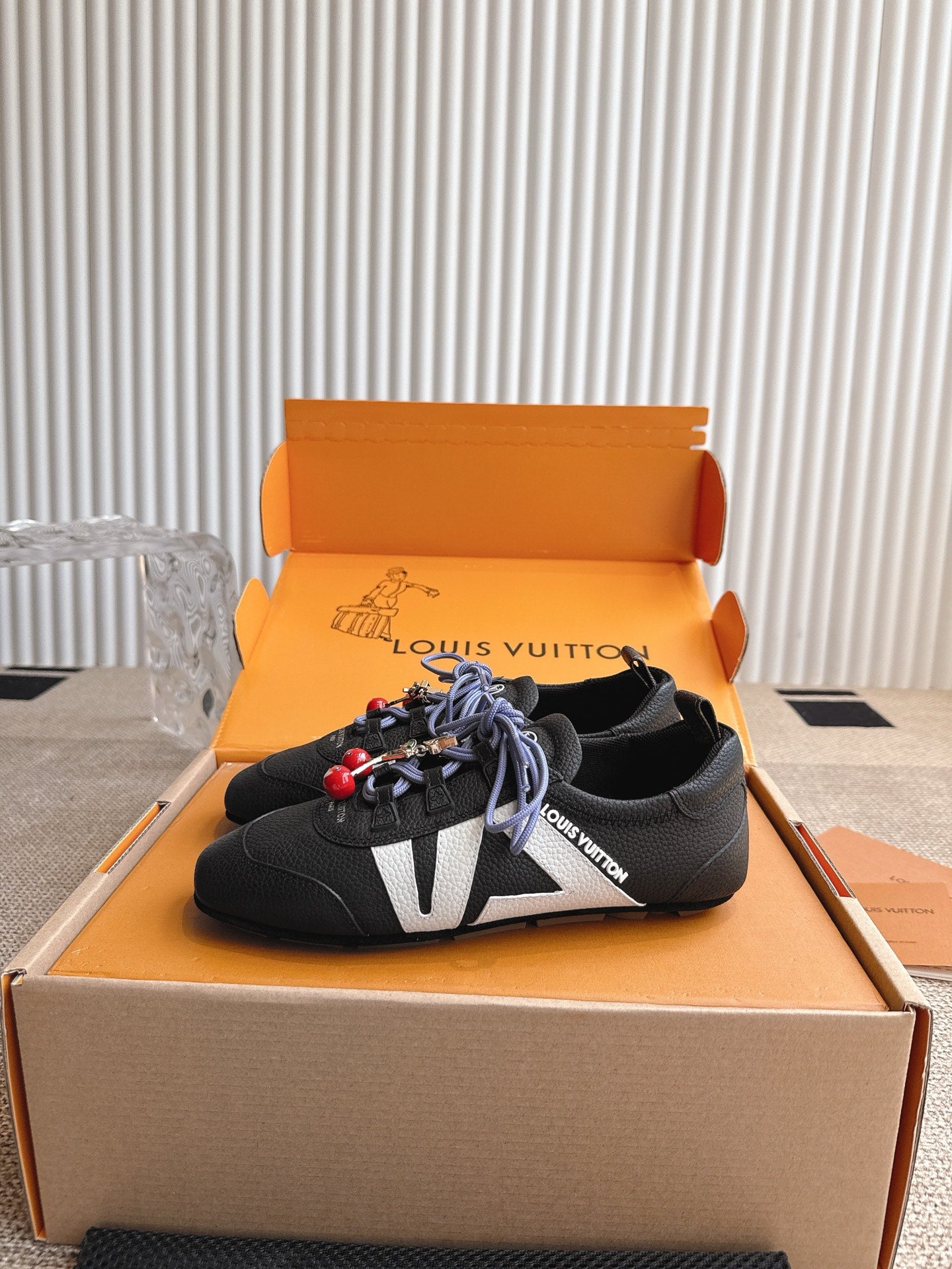 Louis Vuitton unisex sneakers in black with blue laces, red charms, and white V detail