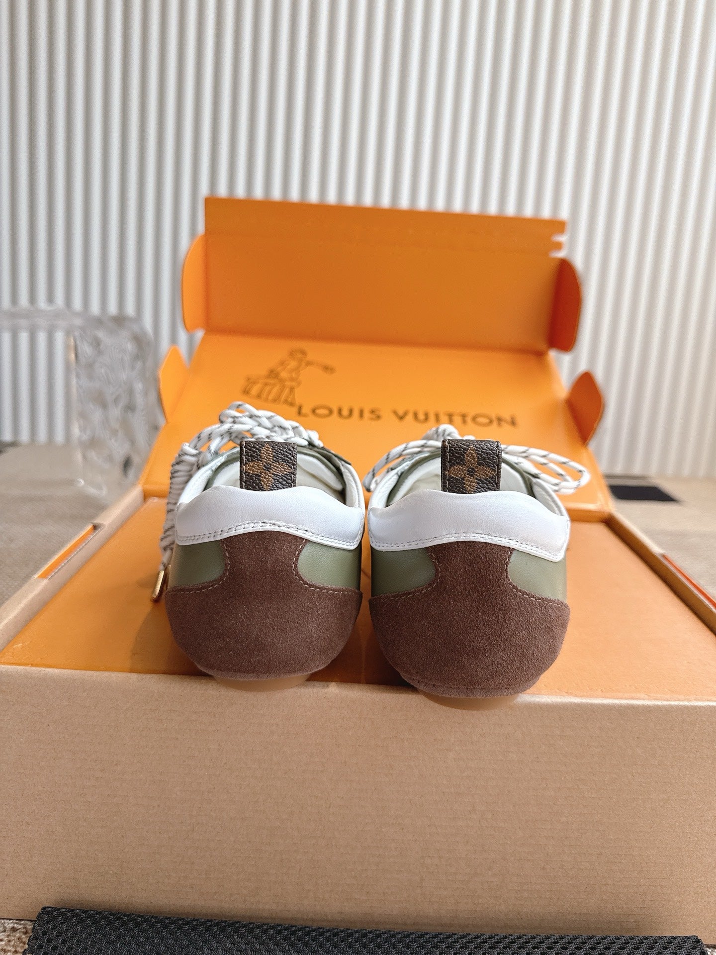 Back view of low-top sneakers, white heel tabs, olive uppers with brown soles.