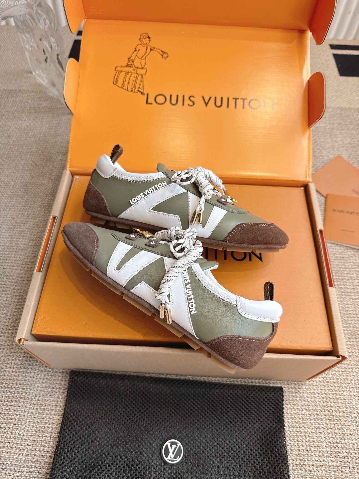 Low-top sneakers, olive and brown leather, white laces with charm and ribbon detail.
