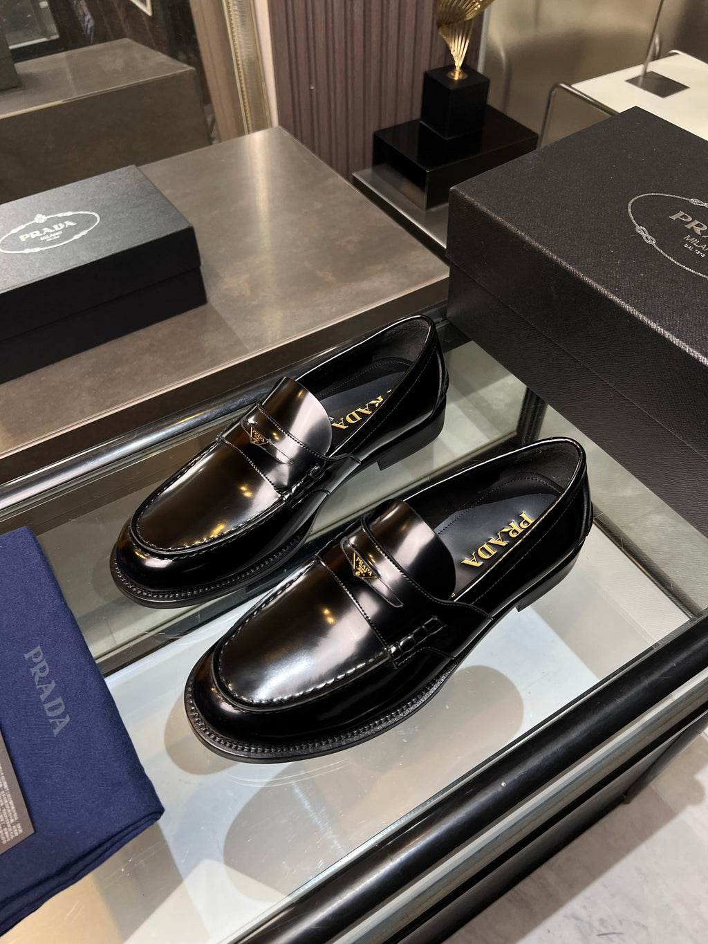 Prada unisex shoes: black patent leather loafers with gold buckle detail, side-by-side