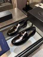 Prada unisex shoes: black patent leather loafers with gold buckle detail, side-by-side