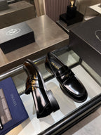 Prada unisex shoes: black patent leather loafers with gold hardware, side view of pair