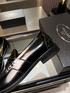 Prada unisex shoes: close-up of black patent leather loafer with gold buckle and stitching
