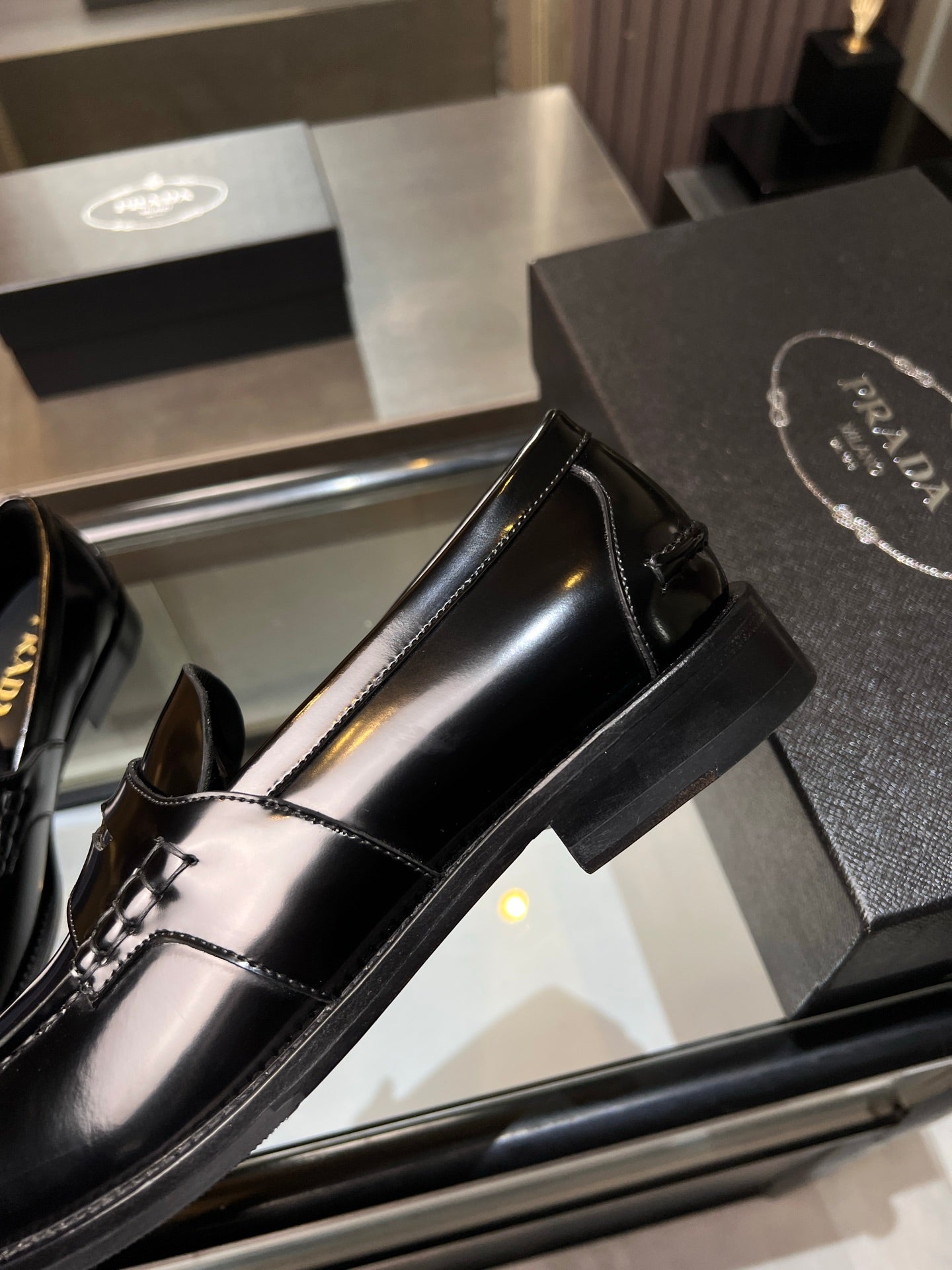 Black leather loafer with gold-tone trim, close-up of side panel