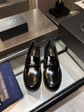 Prada unisex shoes: black patent leather loafers with gold trim, front view of pair