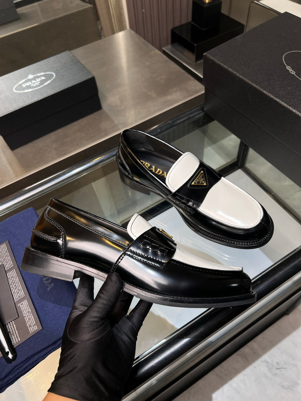Black leather Prada loafer with glossy finish and decorative strap detail.