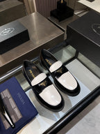 Black and white Prada loafers, gold-trim logo, rounded toe slip-on shoes.