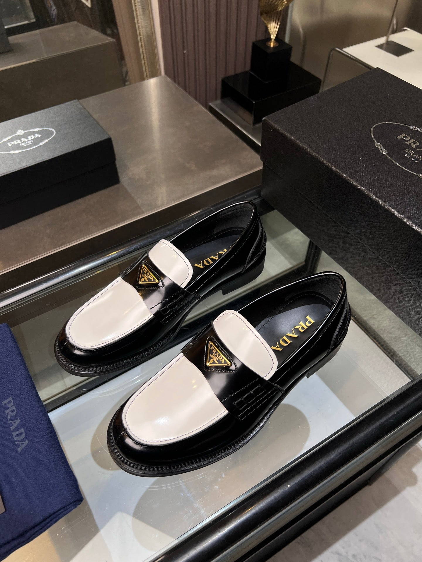 Black Prada loafers with white panels and gold logo, low slip-on design.
