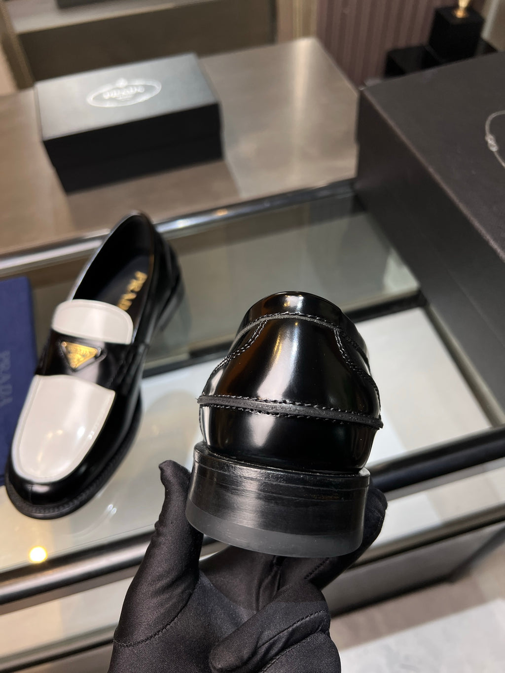 Black Prada loafer back view, cushioned heel and glossy upper with logo detail.