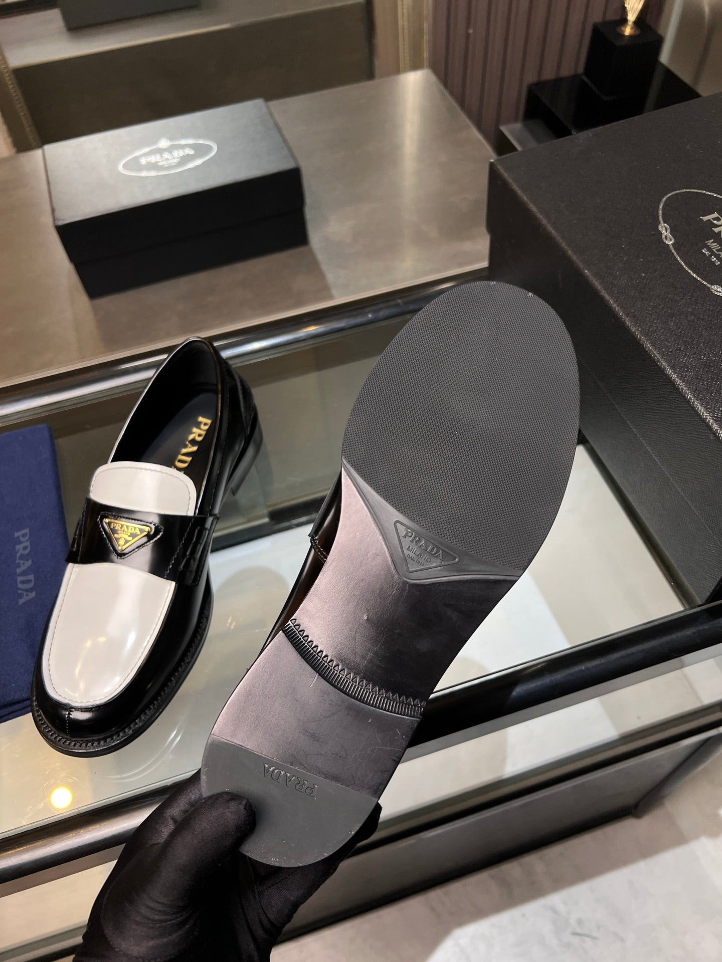 Prada loafers with black upper and white panels; visible rubber sole and heel.