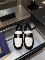 Black and white Prada loafers with gold logo, patent leather slip-on shoes.
