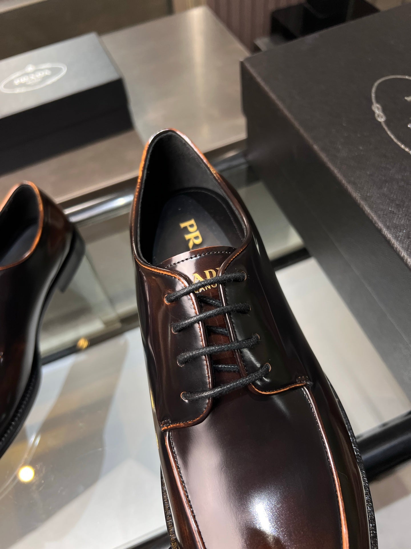 Close-up of dark brown leather lace-up oxford shoe with Prada logo at the collar
