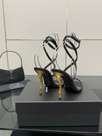 Black strappy heeled sandals with gold-tone stiletto heels and thin ankle straps