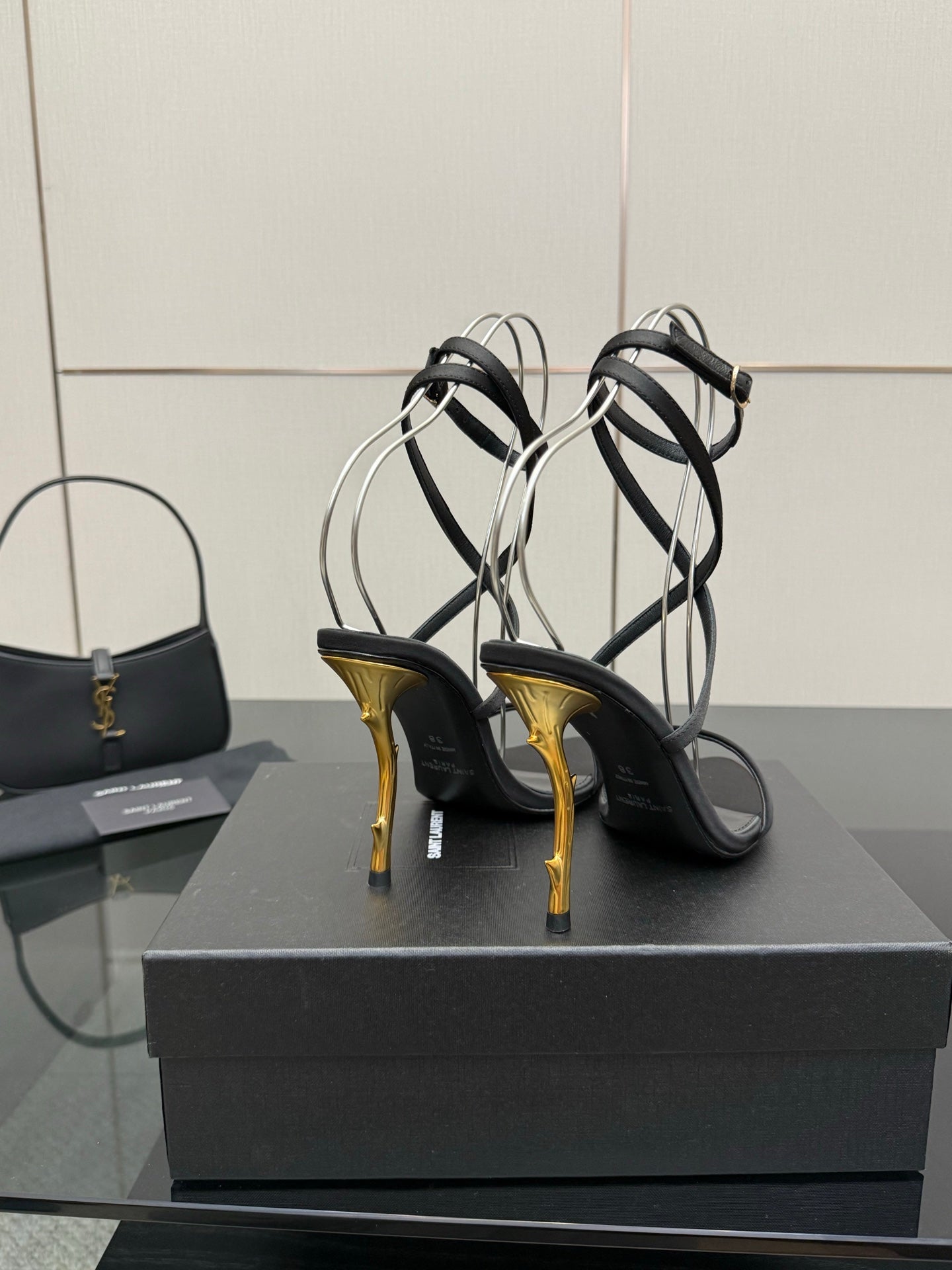 Black strappy heeled sandals with gold-tone stiletto heels and thin ankle straps