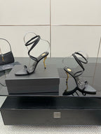 Black strappy heeled sandals with gold-tone stiletto heel and clear-style toe straps