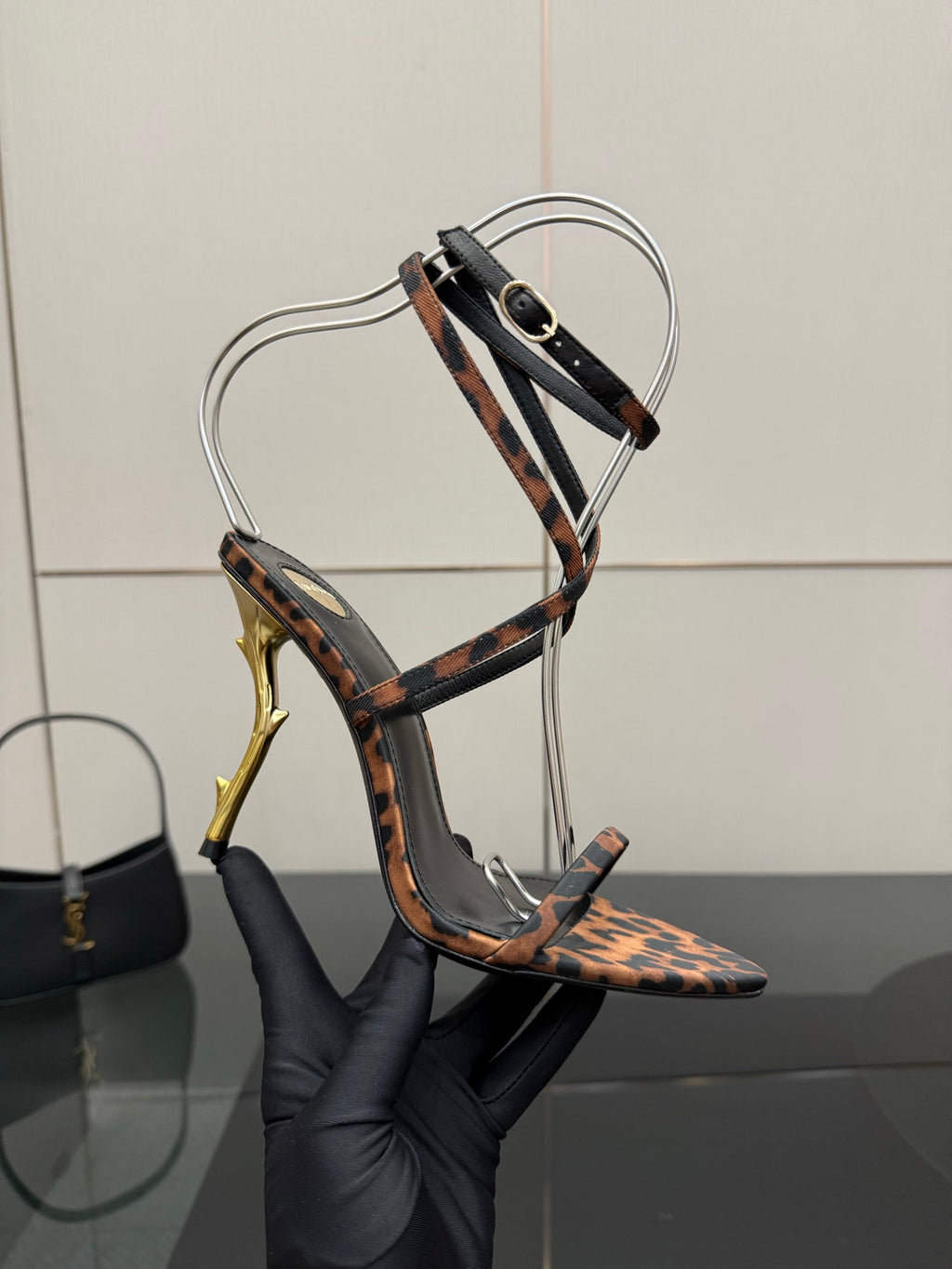 YSL women’s leopard-print sandal with black T-strap and gold-tone stiletto heel, close-up