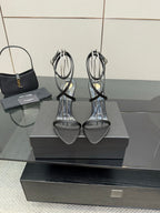 Silver strappy heeled sandals with thin straps and gold-tone heel accents