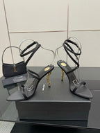 Pair of black strappy heeled sandals with gold-tone stiletto heels and ankle straps