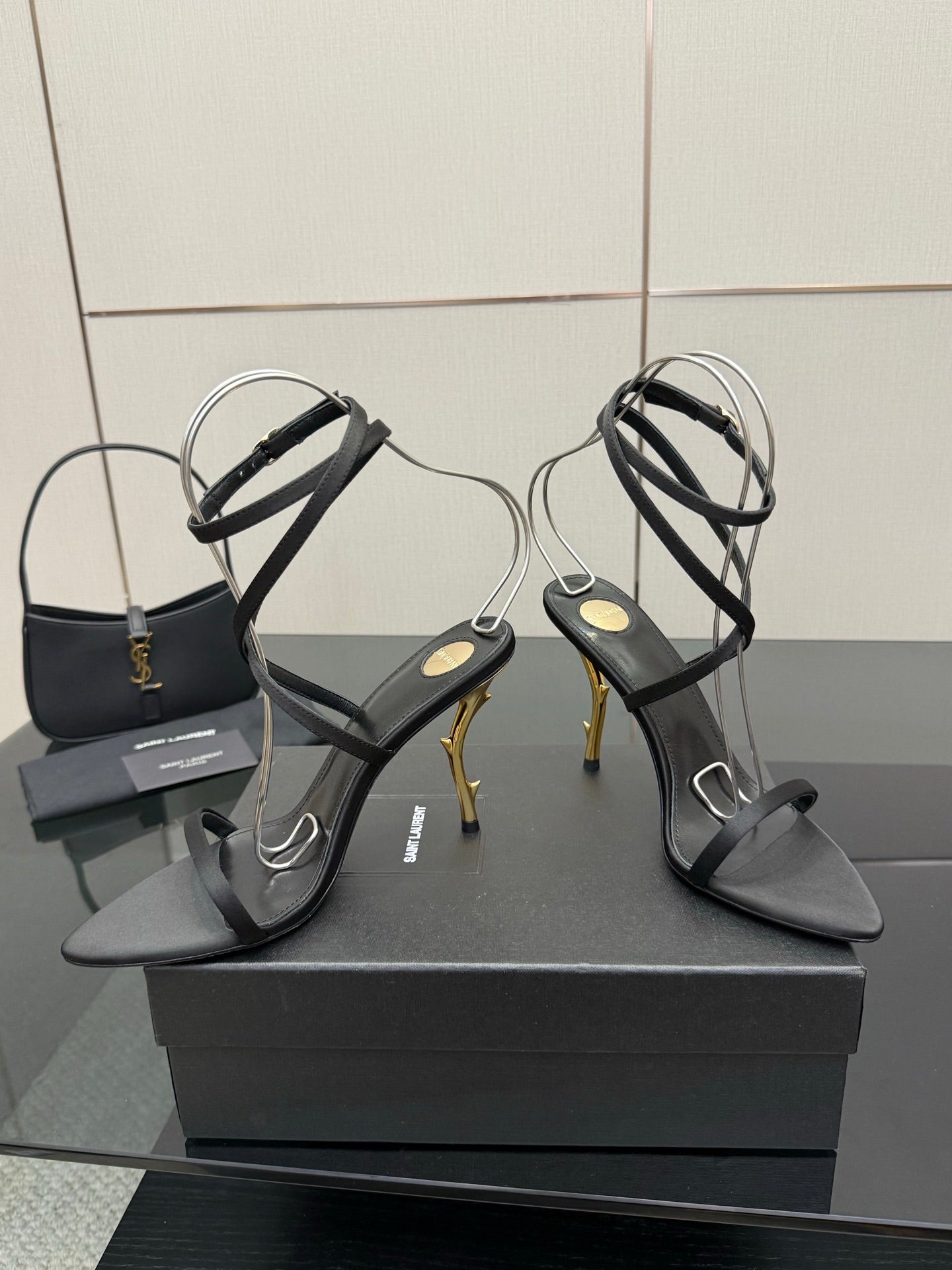 Pair of black strappy heeled sandals with gold-tone stiletto heels and ankle straps