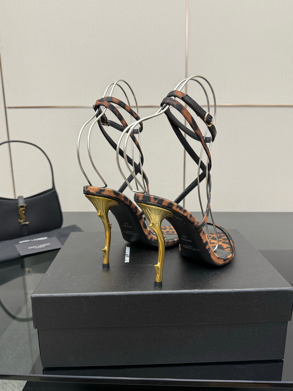 YSL women’s leopard-print heeled sandals with black crisscross straps and gold-tone stiletto heels