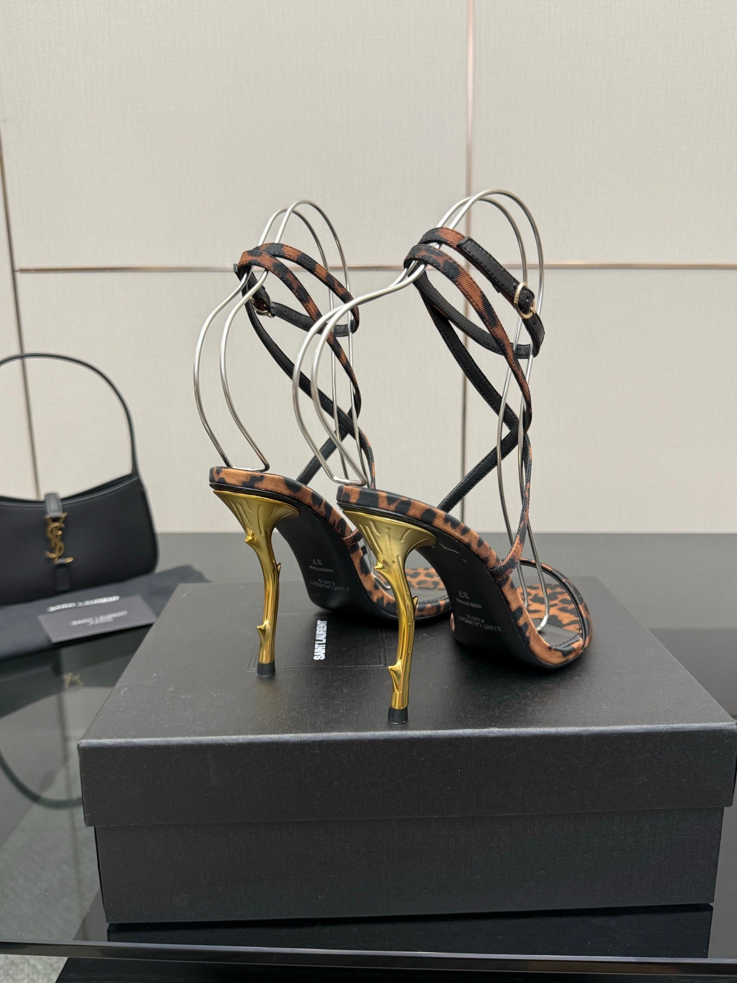 YSL women’s leopard-print heeled sandals with black crisscross straps and gold-tone stiletto heels
