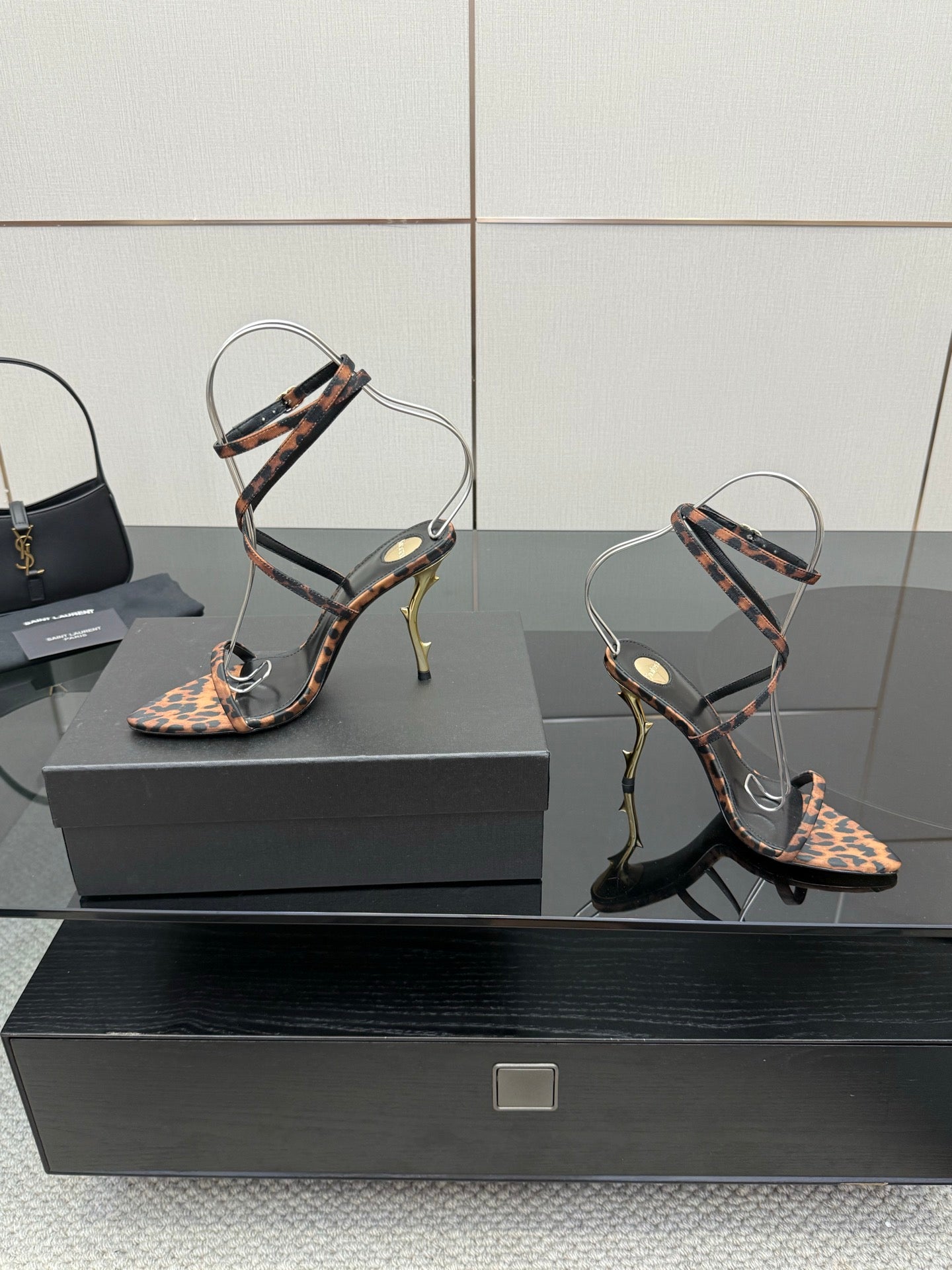 YSL women’s leopard-print heeled sandals with black straps and gold-tone stiletto heels, side view