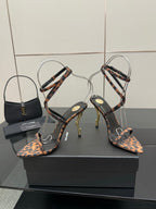 YSL women’s leopard-print heeled sandals with thin black ankle straps and gold-tone stiletto heels