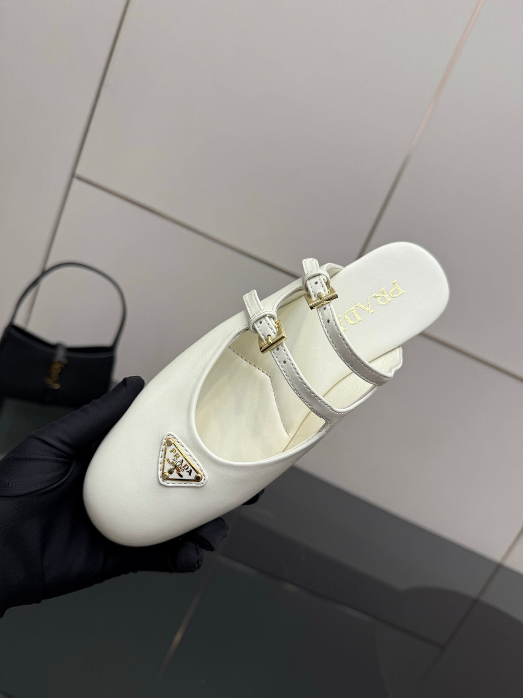 Women's Prada white leather flat with double buckle straps, close side view