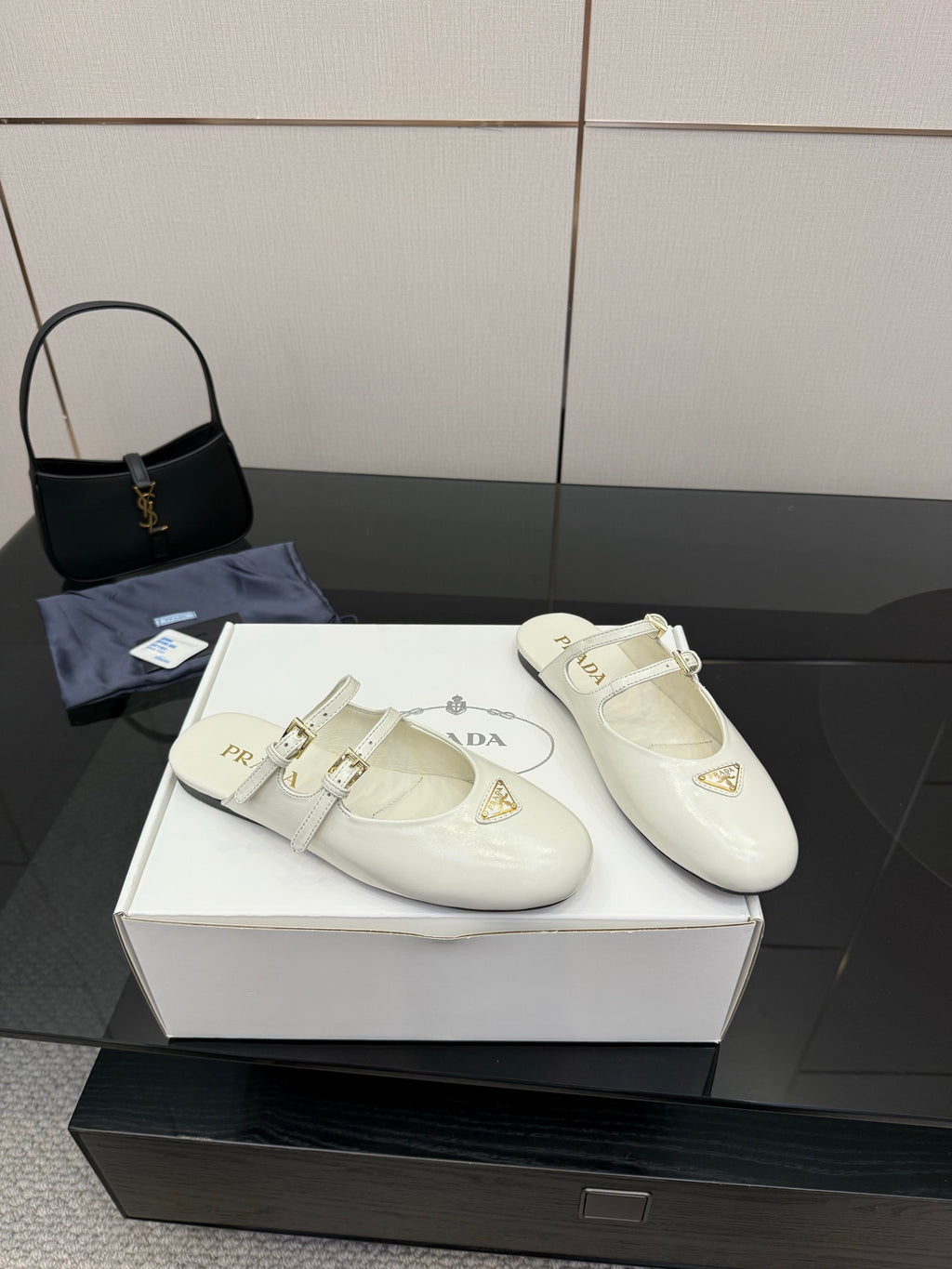 Pair of women's Prada white leather flats with double buckle straps and logo triangle detail
