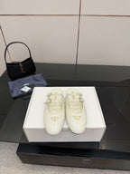 Women's Prada white leather flats with double buckle straps and triangular logo detail