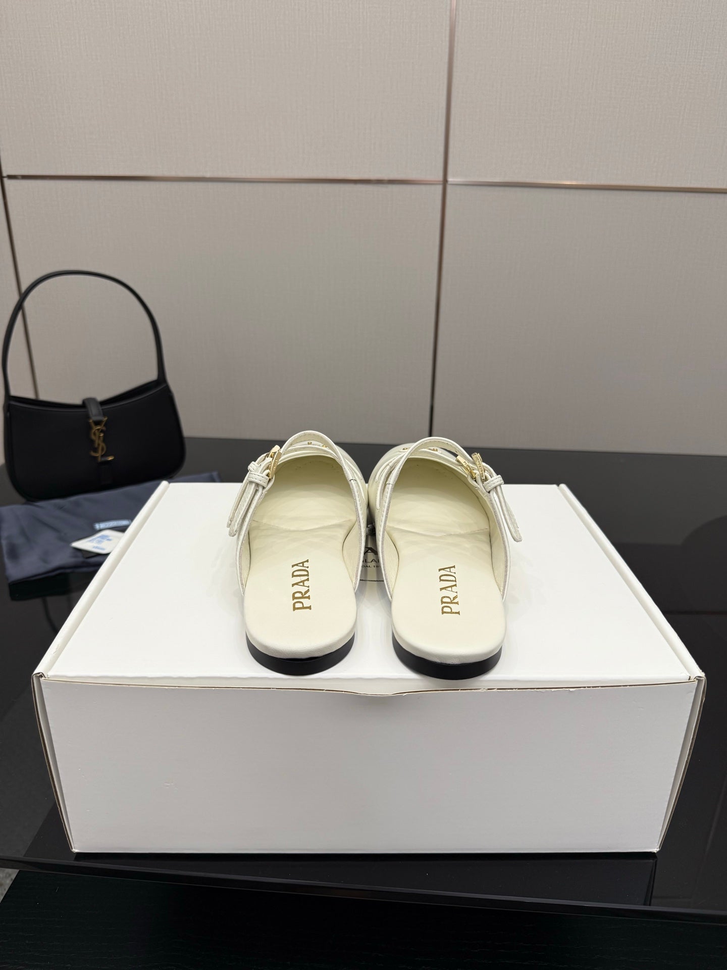Women's Prada white leather slide flats with double buckle strap, shown on display box