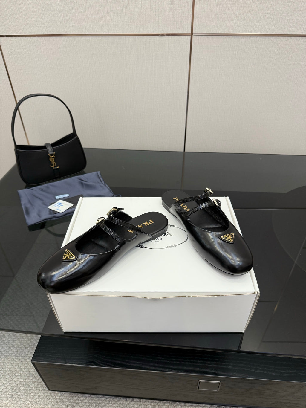 Women's black Prada slip-on shoes with gold buckle and decorative emblem