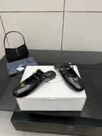 Women's black Prada slip-on shoes with gold buckle and decorative emblem
