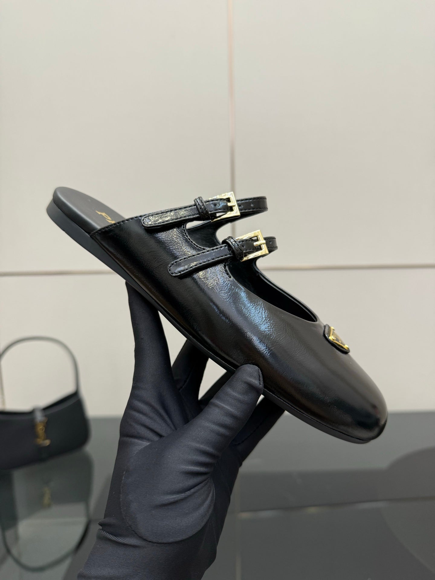Women's black leather Prada slip-on shoe with gold buckle and emblem patch