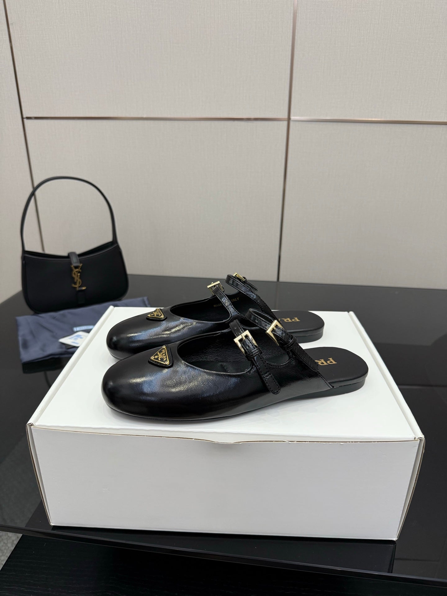 Women's black leather Prada slip-on shoes with front buckle strap