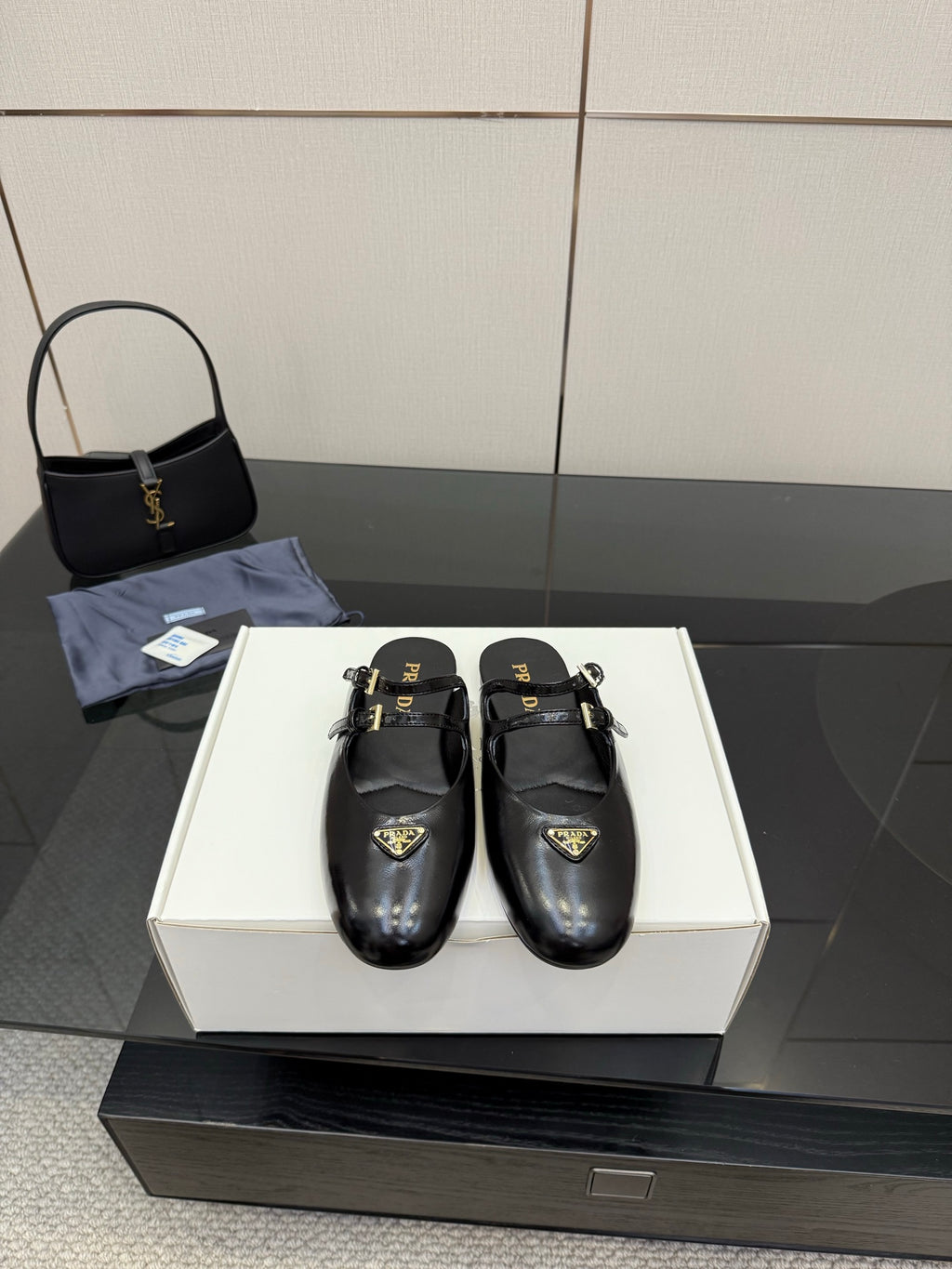 Women's black leather Prada slip-on shoes with gold buckle detail