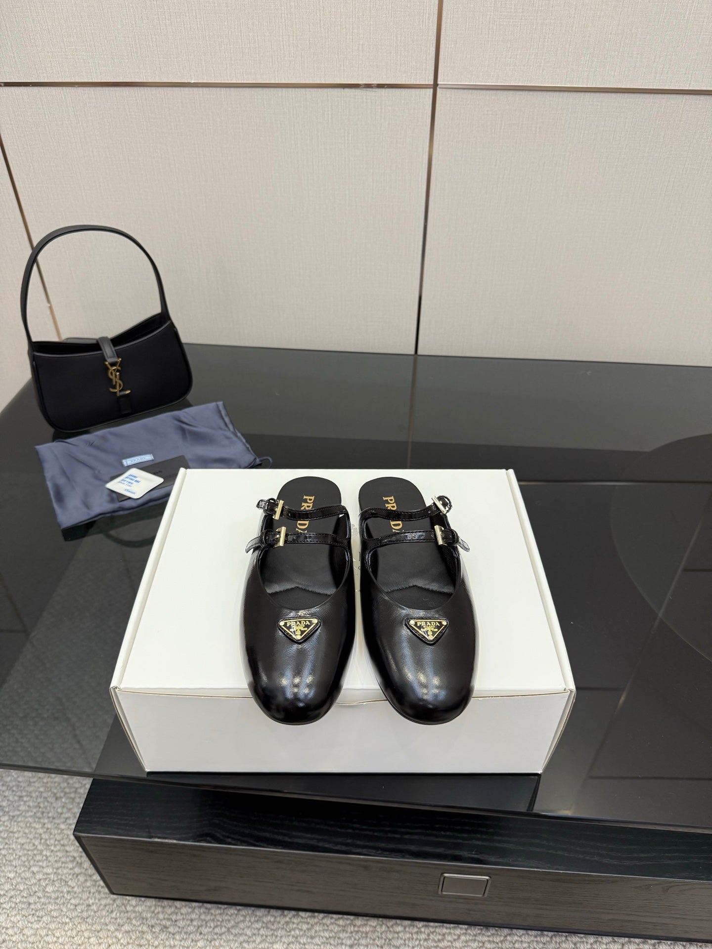 Women's black leather Prada slip-on shoes with gold buckle detail