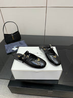 Women's black leather Prada slip-on shoes, gold-trimmed strap and logo tag