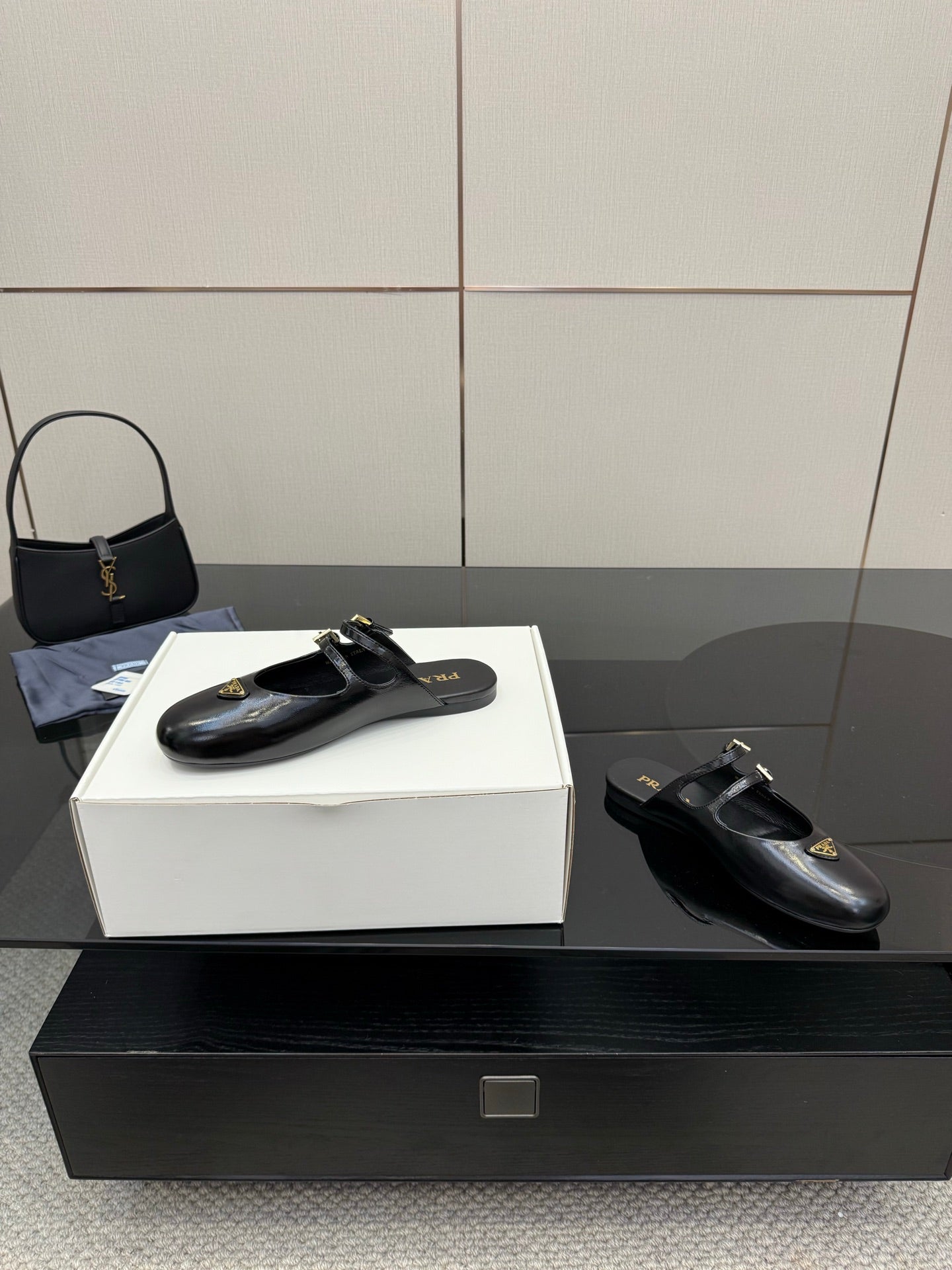 Women's black leather Prada slip-on shoes with gold buckle hardware detail