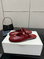 Red leather open-strap mule flats with gold buckle hardware and logo emblem