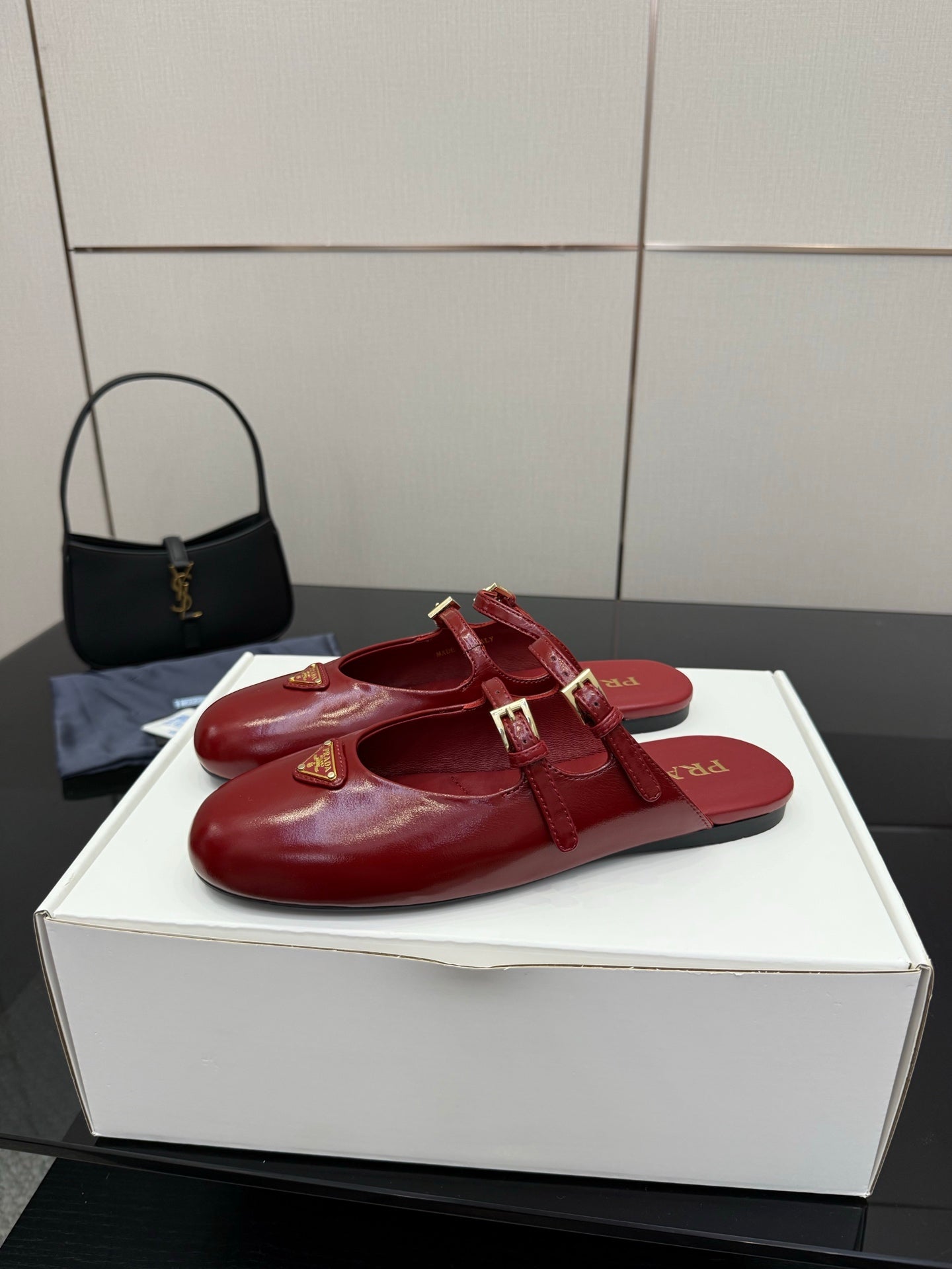 Red leather open-strap mule flats with gold buckle hardware and logo emblem