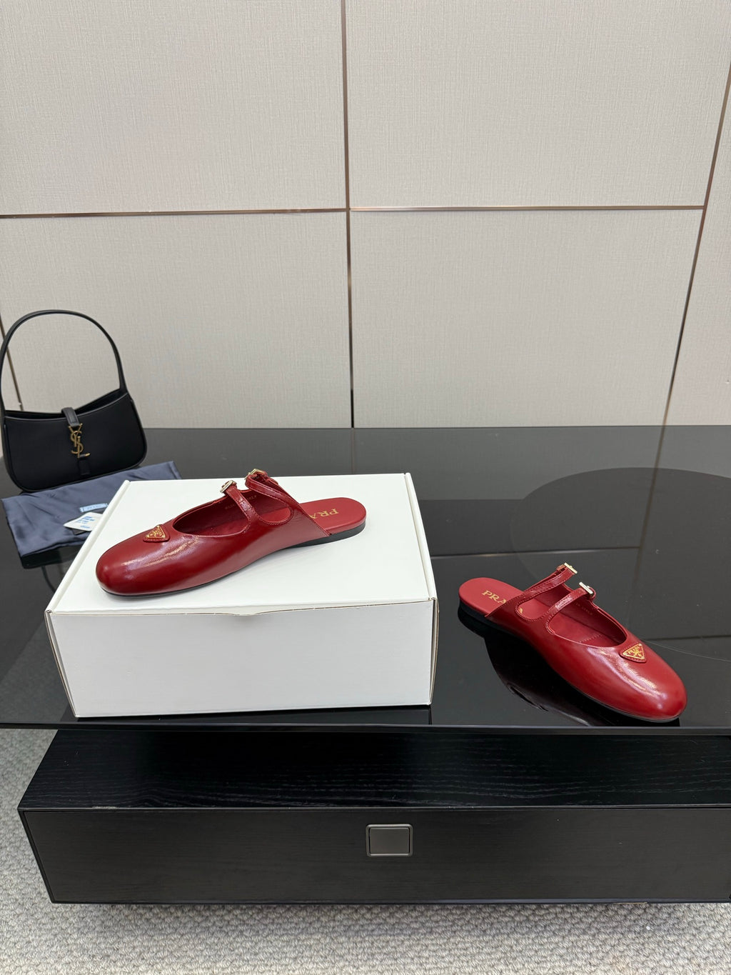 Red leather mule flats with gold buckle detail, side view on display box