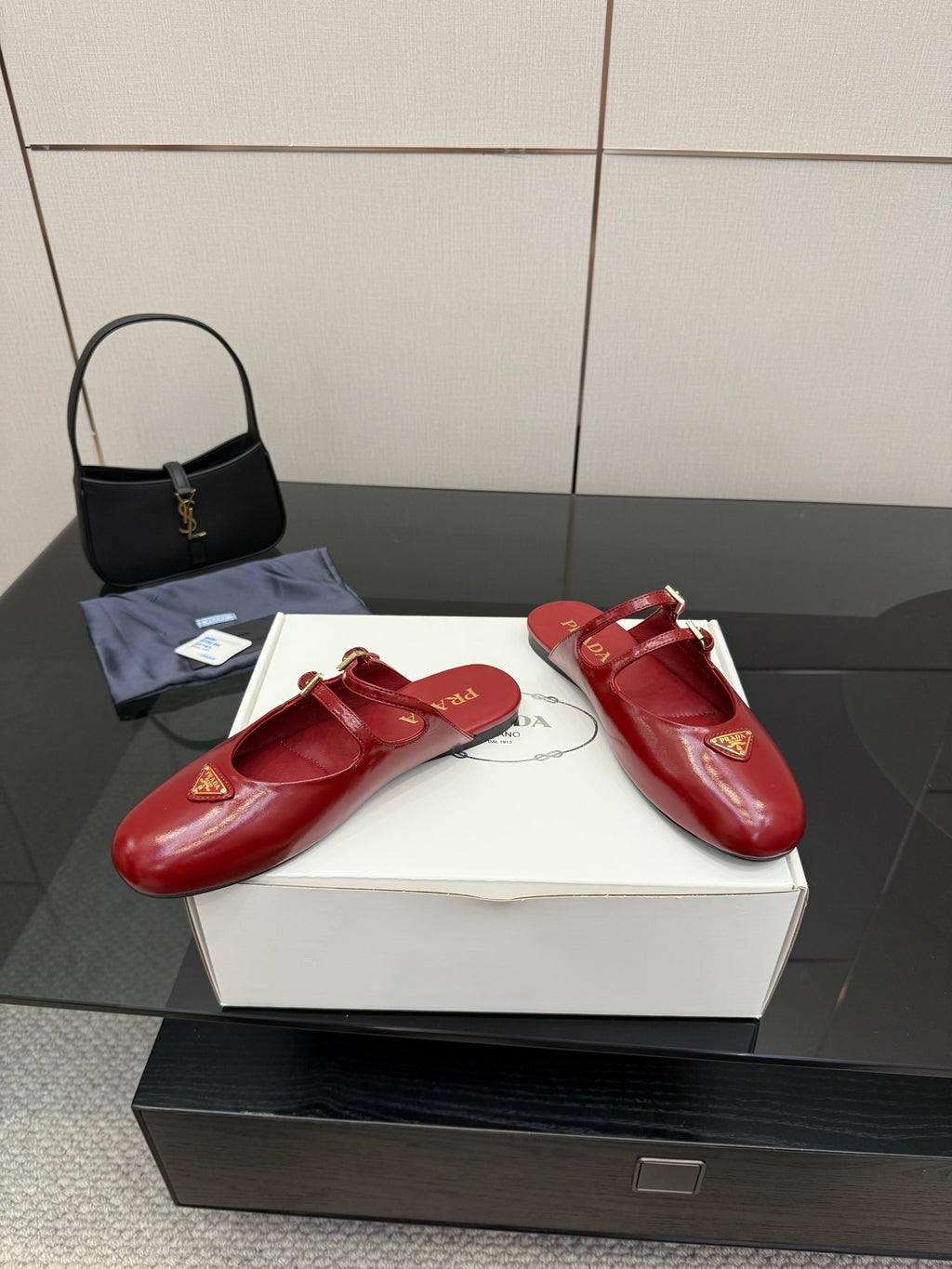 Red leather mule flats with gold buckles and logo emblem, shown on box