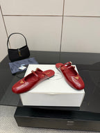 Red leather mule flats with gold buckles and logo emblem, shown on box