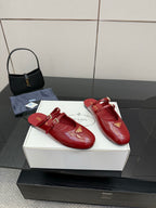 Pair of red leather mule flats with gold buckle detailing and logo emblem