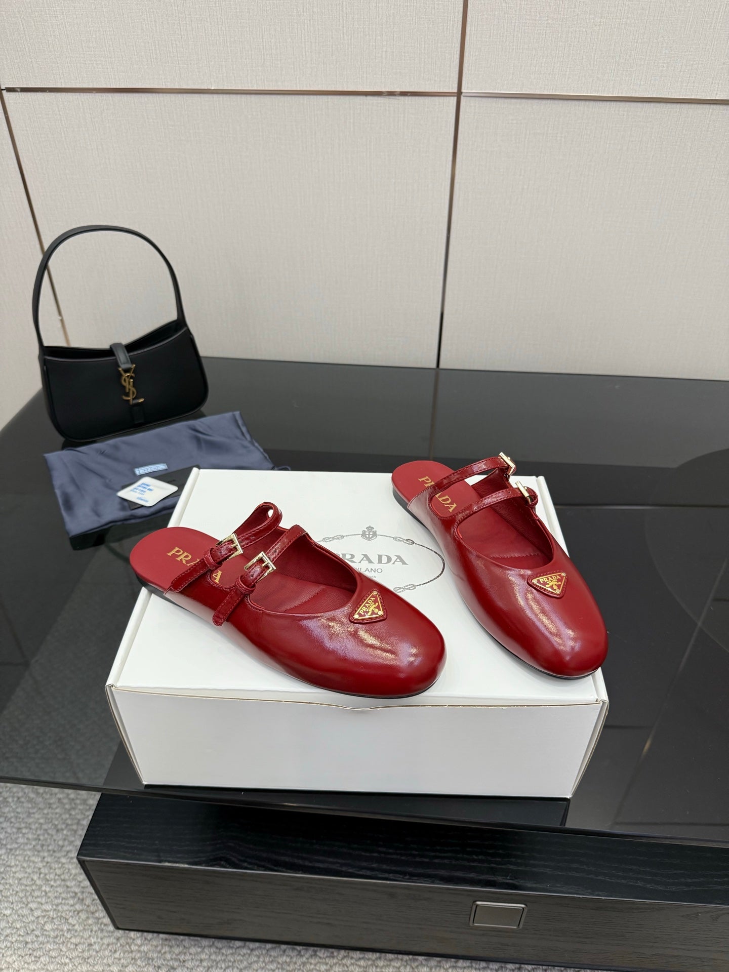 Pair of red leather mule flats with gold buckle detailing and logo emblem
